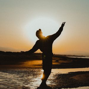 Silhouette of a person in a balancing yoga pose at sunrise.